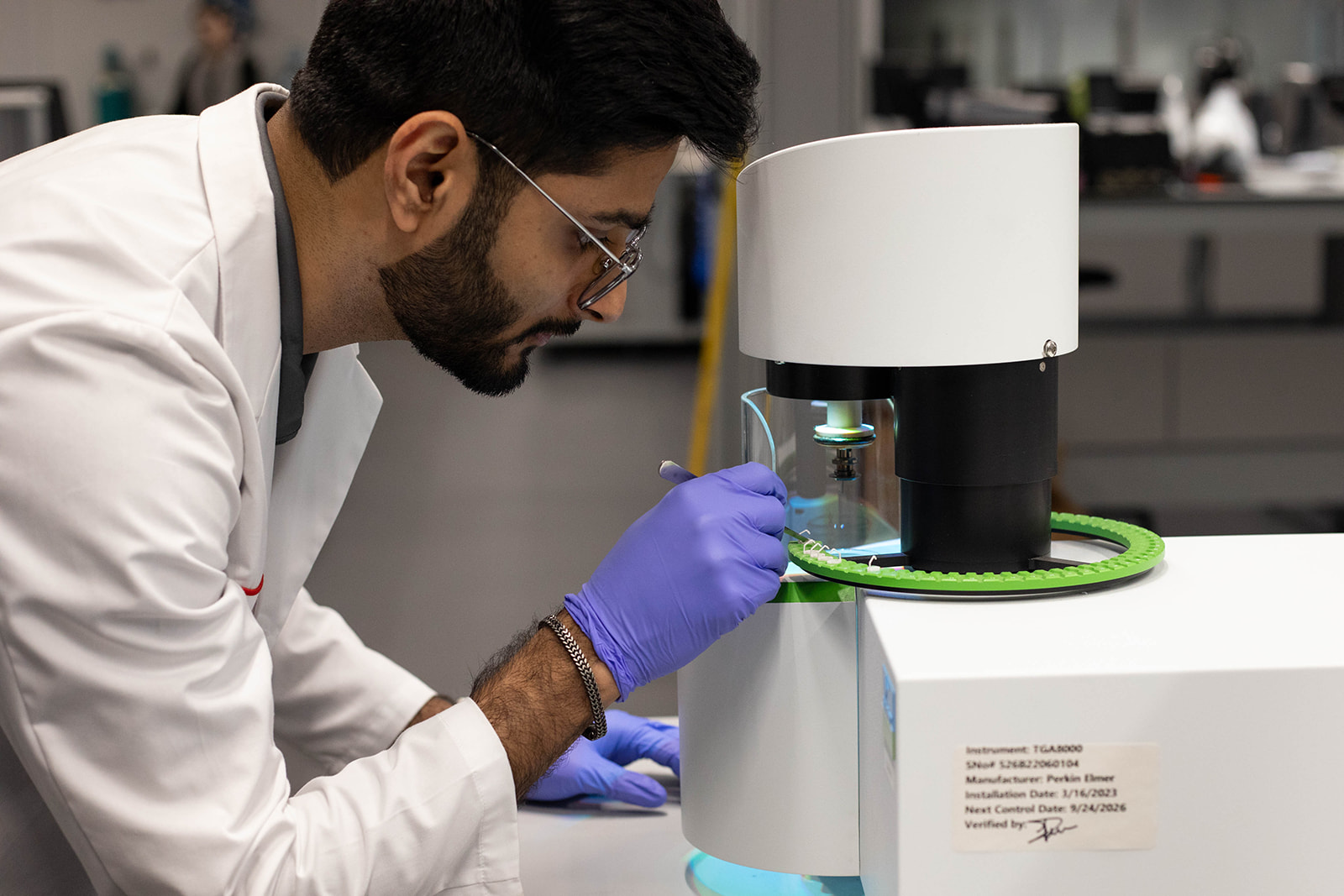 Lab technician loading a sample into the TGA analyzer for testing